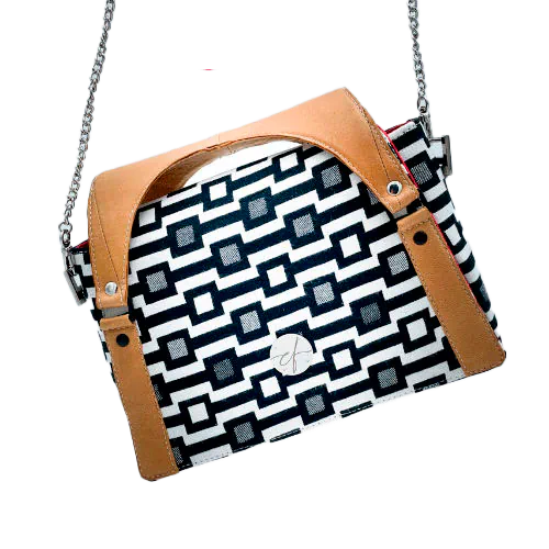 Un sac à main fait en écharpe de portage noir et blanc motif géométrique, cuir caramel et popeline rouge.