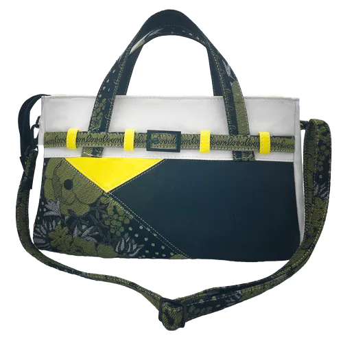 Un sac long et peu haut confectionné avec des cuirs jaune, blanc et noir et un coupon d'écharpe de portage au motif floral en noir, jaune et blanc, avec une doublure de toile jaune.
