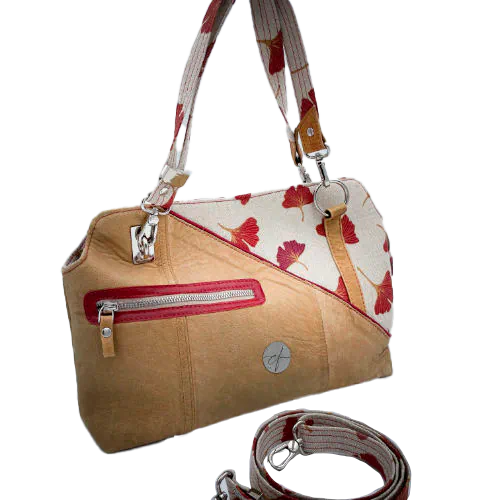 Un sac à main fait d'un cuir de couleur camel et une toile en polycoton avec un motif de feuilles de Ginkgo Biloba rouges.