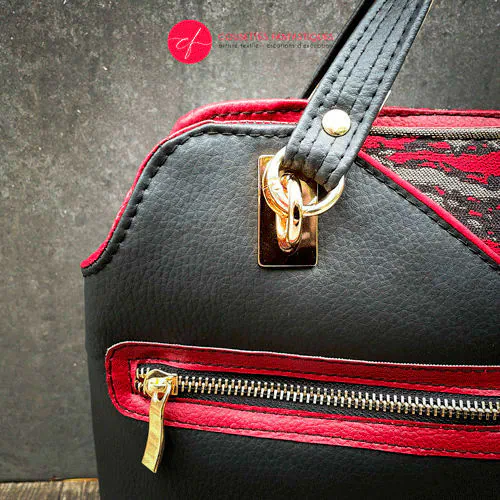 Un sac d'épaule fait en similis noir, doré et rouge, et tissu d'écharpe dans les mêmes tons, motif marbré.
