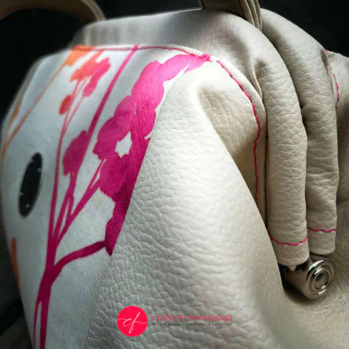 Un petit sac à main constitué de simili crème et tissu d'ameublement crème, au motif végétal dégradé de rose à orange.