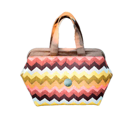 Un sac à main fait en tissu d'écharpe au motif chevron géant dans les tons d'automne (rose, marron, orange, jaune et blanc).
