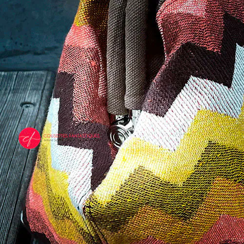 Un sac à main fait en tissu d'écharpe au motif chevron géant dans les tons d'automne (rose, marron, orange, jaune et blanc).
