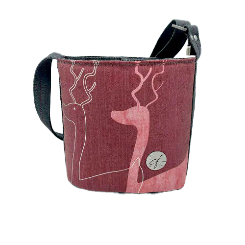 Un petit sac dit “seau” fait avec toile fine rose présentant deux silhouettes de cerfs blanches, et du denim haute-couture gris.