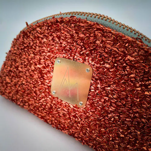 Une pochette zippée fabriquée à partir d'un tissu extensible avec du bouclé métallique cuivré, du similicuir bleu turquoise, et une doublure menthe clair.